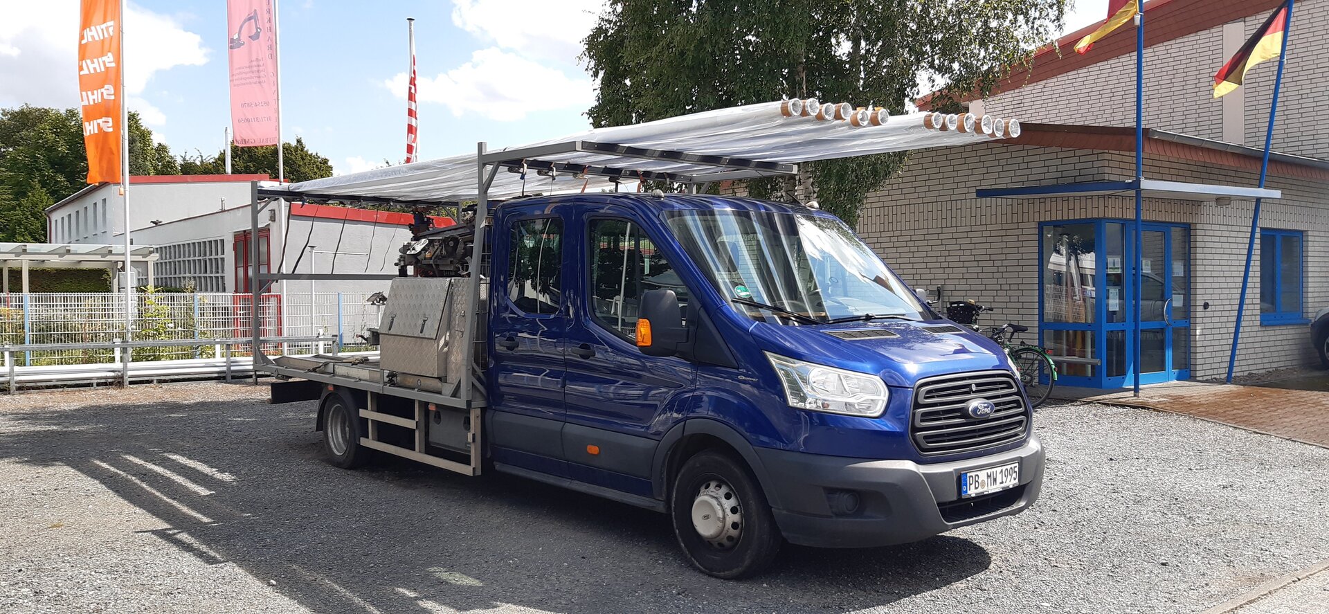 Blauer Transit mit 12 Fahnenmasten beladen