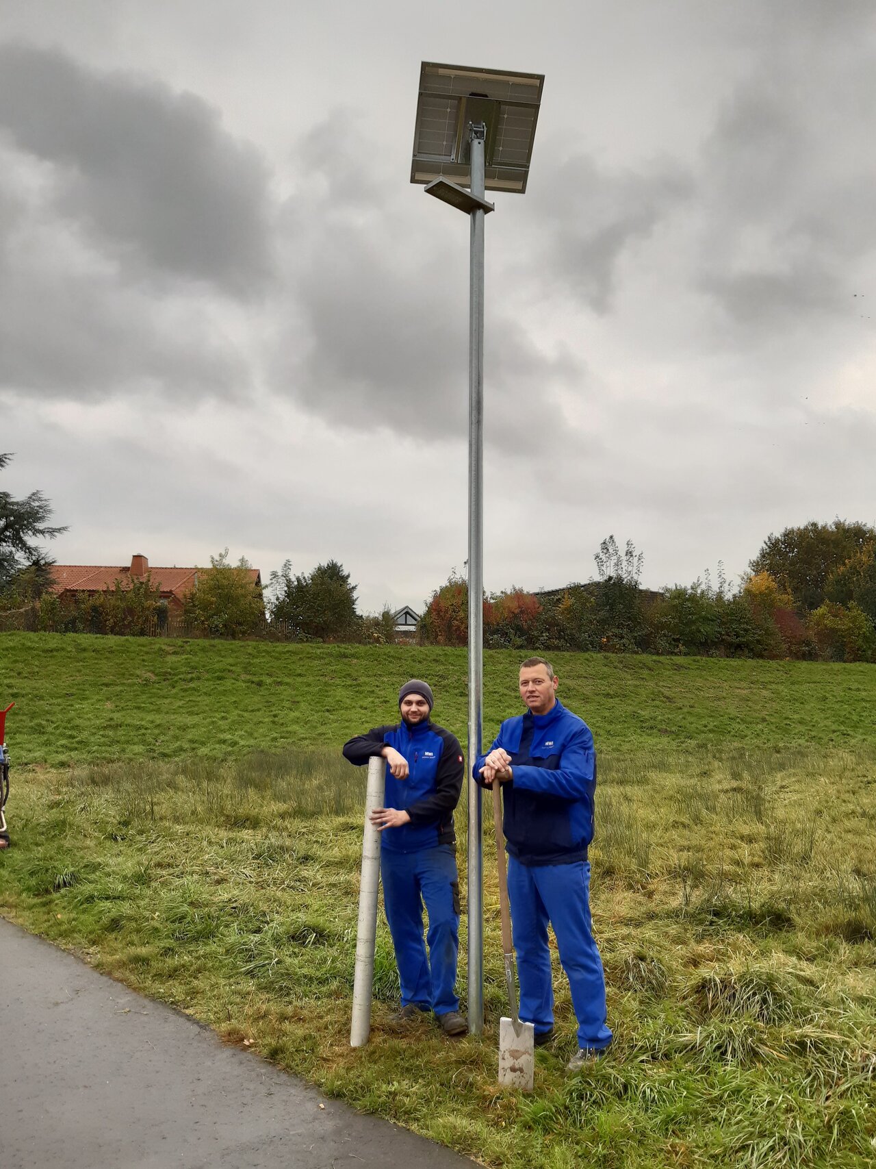 2 Monteure haben eine MWI-Solarleuchte fertig montiert mit Schraubfundament in der Werre-Flutmulde Bad Oeynhausen