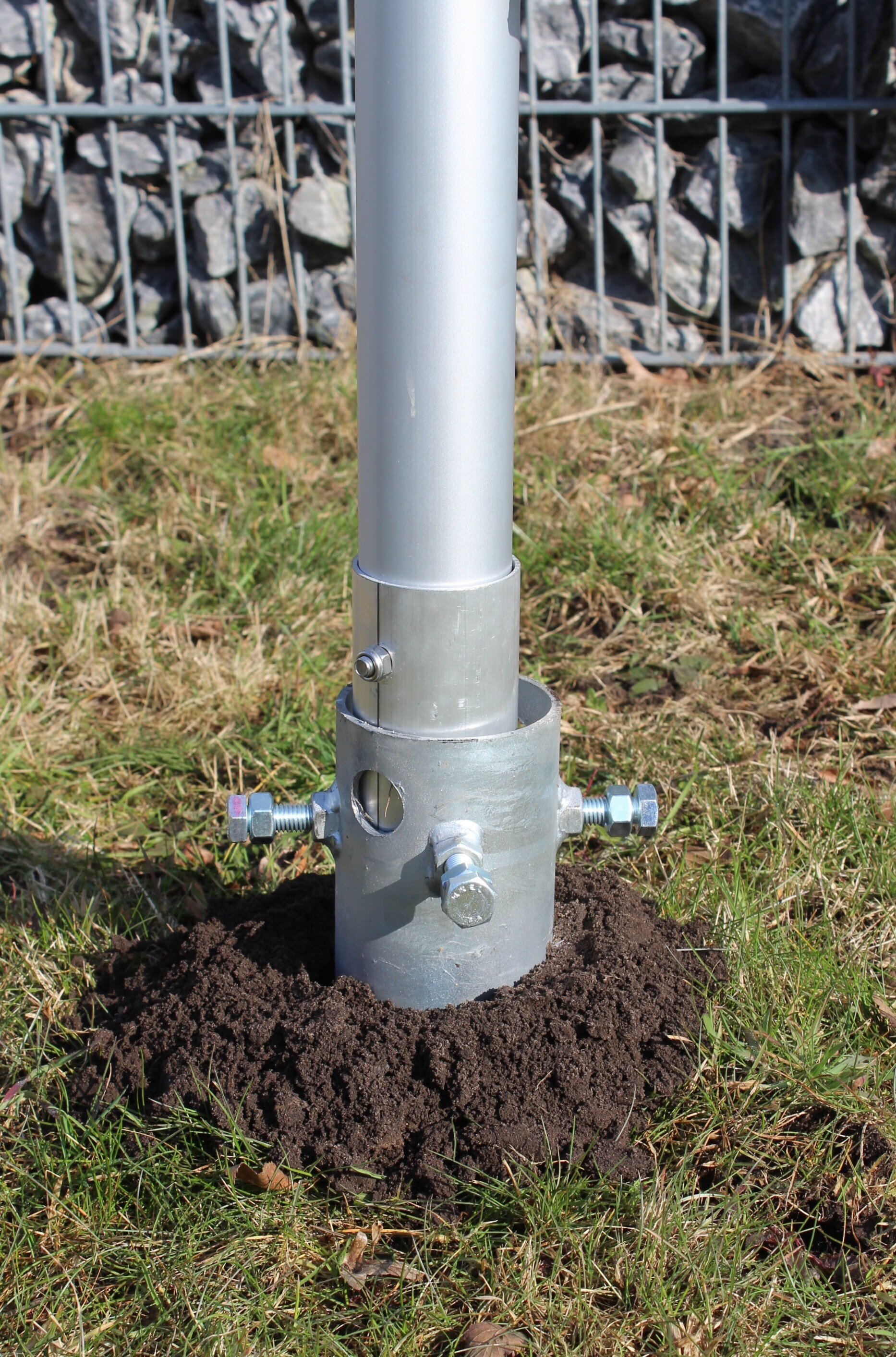 montiertes Schraubfundament mit Klemmschrauben, Bodenhülse im Schraubfundament fixiert und Fahnenmast aufgestellt